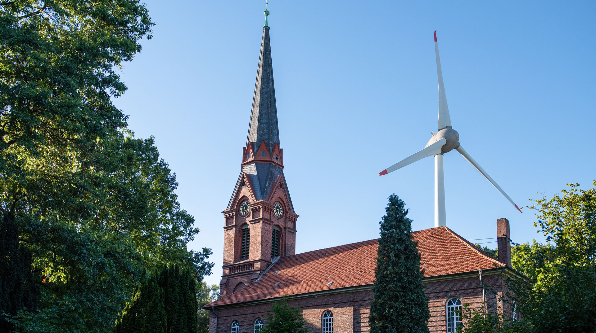 Sankt Gertrudkirche Altenwerder am 6. September 2023 in Hamburg. Hinter dem Kirchturm ist ein Windrad zu sehen. Bild: Michael Althaus/KNA